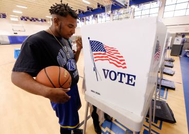 A man holds his basketball while receiving assistance from an election official at a recreation center serving as polling place.